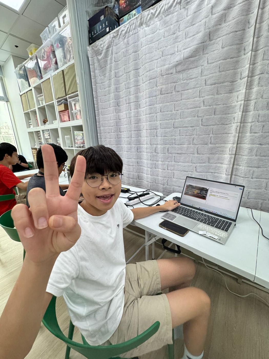 學生在電腦前笑着做出勝利手勢